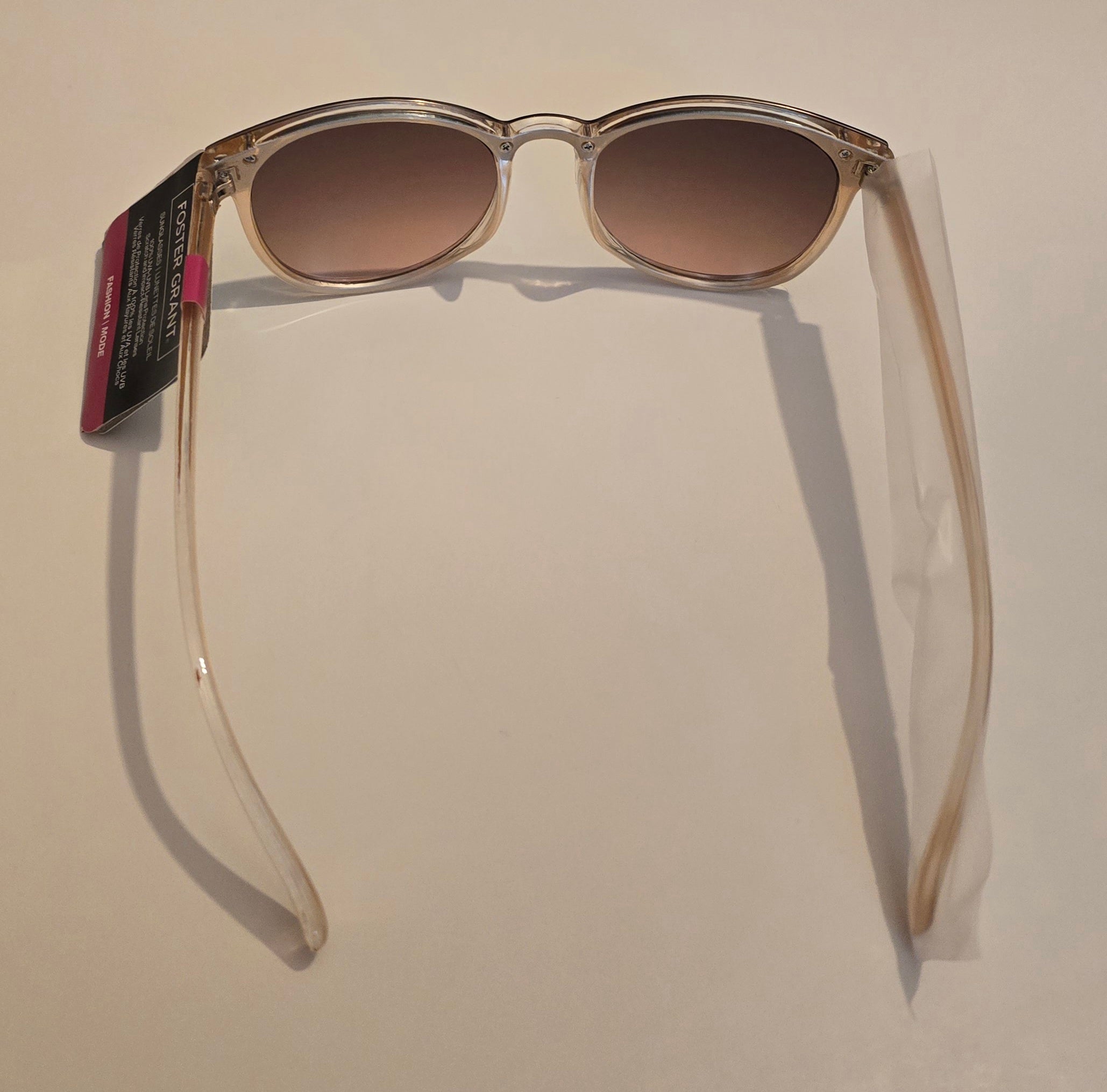 Sunglasses with a clear frame and brown gradient lenses on a beige background